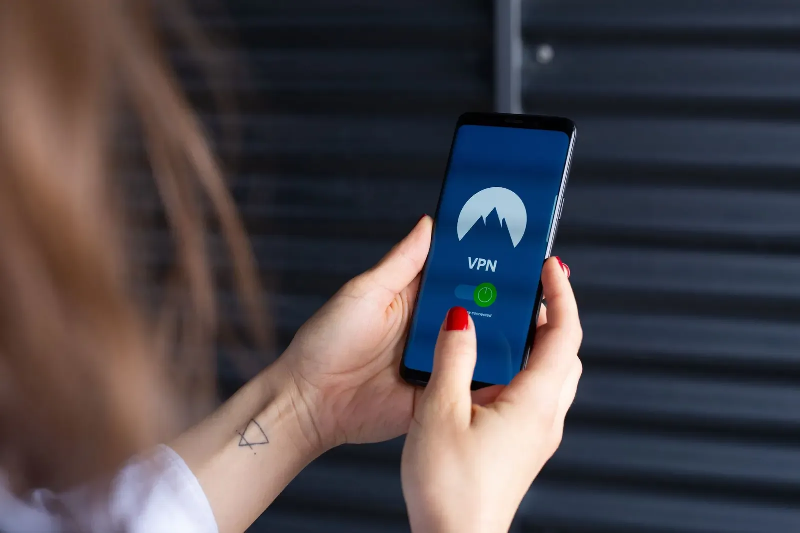 Gros plan des mains d'une femme utilisant une application VPN sur un smartphone, mettant en avant la sécurité