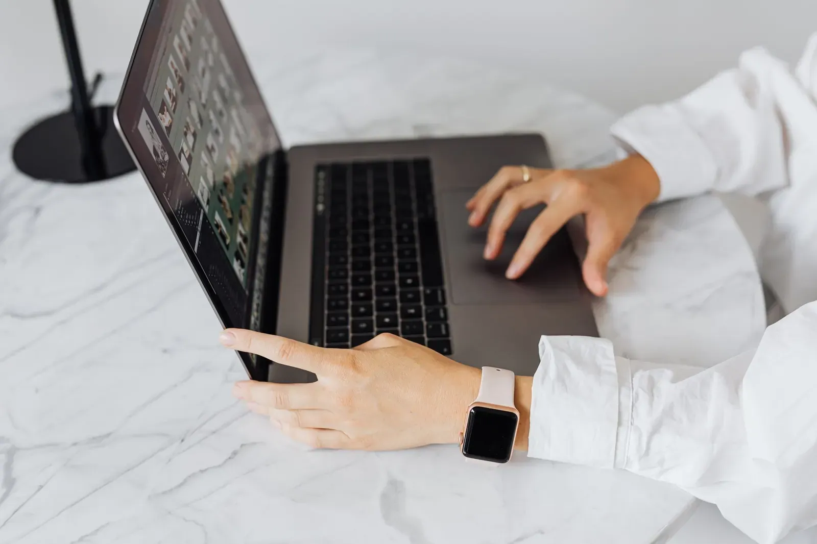 Personne tapant sur un ordinateur portable à une table en marbre, portant une montre intelligente