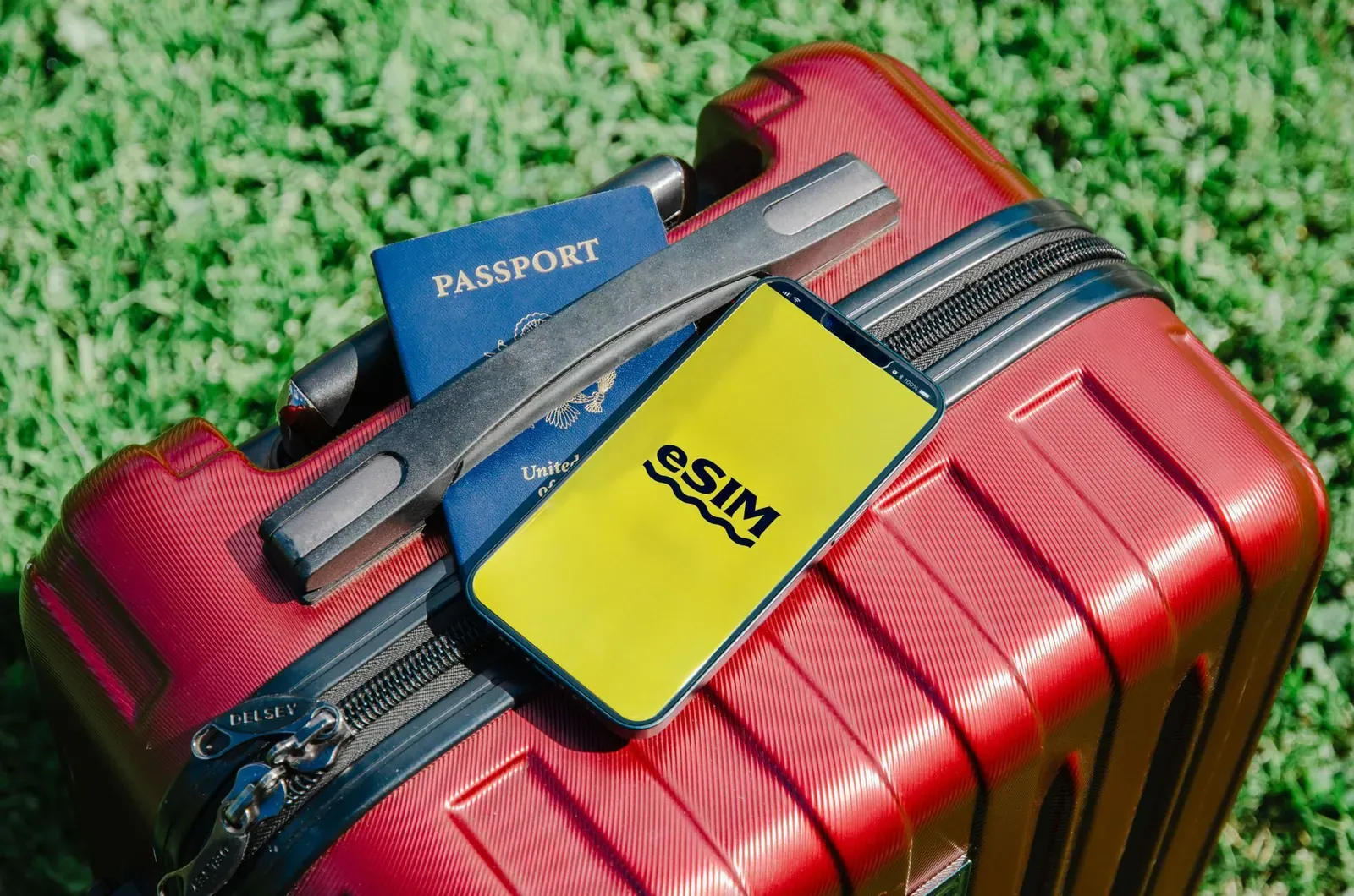 Gros plan sur une valise rouge avec un smartphone affichant eSIM et un passeport, symbolisant la préparation