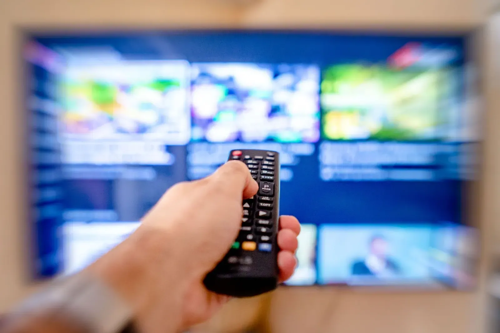 Une main pointe une télécommande vers un téléviseur qui affiche des applications