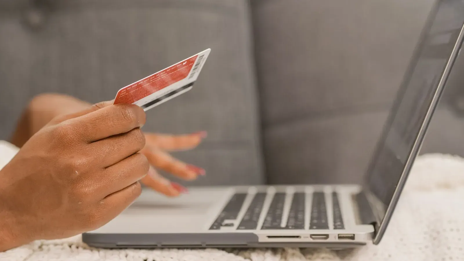 Une main tient une carte bancaire devant un ordinateur portable ouvert