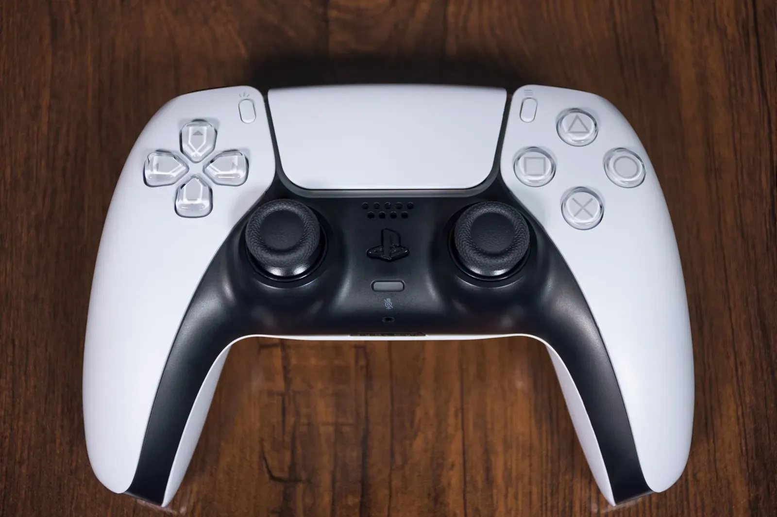 Une manette de console blanche et noire posée sur une table en bois