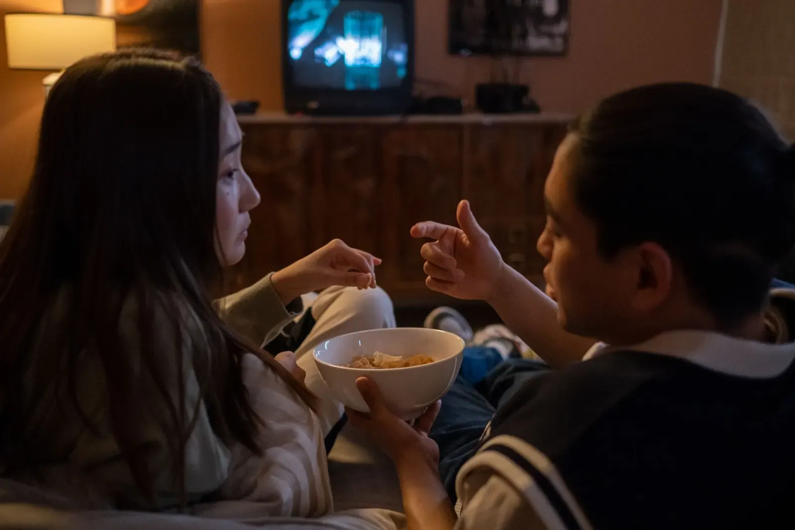 Deux amis regardent la télévision le soir, un bol de pop-corn à la main