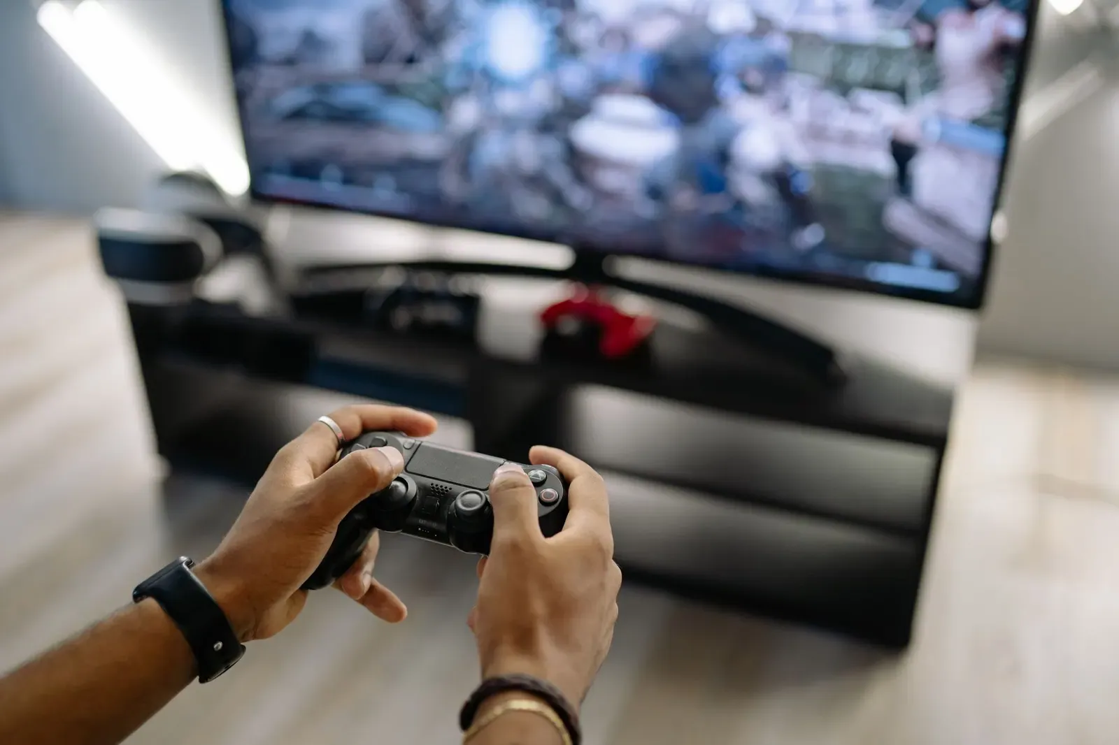 Un joueur tient sa manette devant un téléviseur, vu par-dessus l'épaule