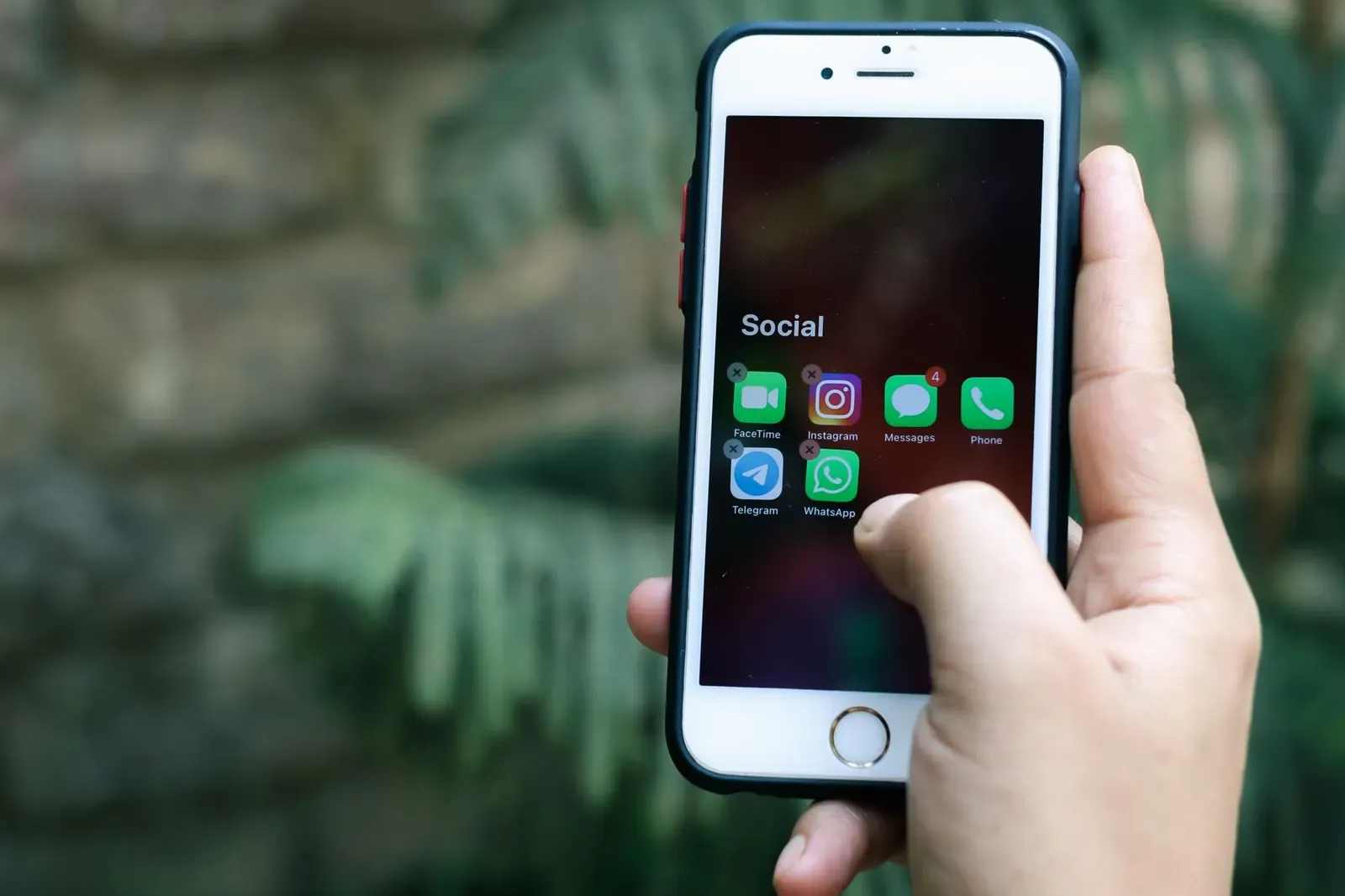 Gros plan sur une main tenant un smartphone affichant des applications de réseaux sociaux en plein air